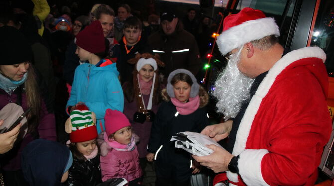 Einer von vielen Weihnachstmännern verteilte Geschenkpäckchen an Kinder