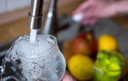 Trinkwasser läuft aus dem Wasserhahn in einer Küche in ein Glas. 