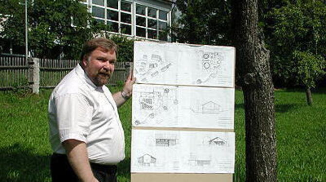 Pfarrer Siegbert Ammann präsentiert die Baupläne fürs Gemeindehaus auf dem Bauplatz. Im Hintergrund die Festhalle.
GEA-FOTO: SCHÜRER