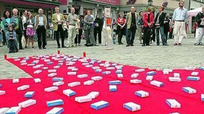 Die Medikamentenschachteln auf der roten Schleife auf dem Tübinger Holzmarkt sollen der Forderung nach preiswerten Medikamenten Nachdruck verleihen.
FOTO: SCHREIER