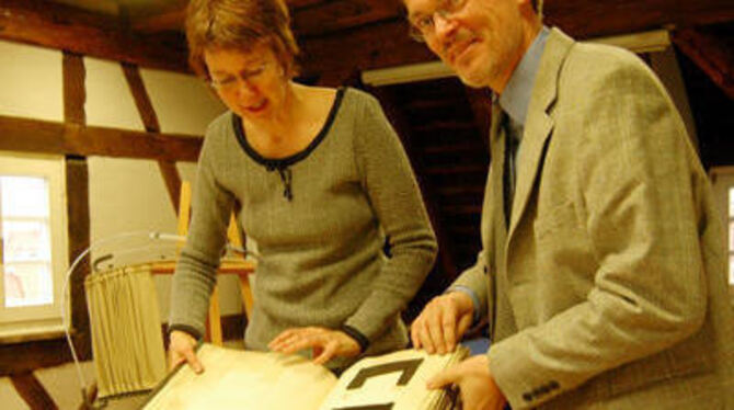 Früher ein Lehrbuch für die Schüler der Webschule: Martina Schröder und Harald Dallmann mit einem Stoffmusterbuch aus London von 1878.
FOTO: NIETHAMMER