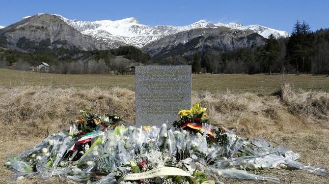 Blumen liegen vor einer Gedenktafel in Le Vernet, für die Opfer der Flugkatastrophe. Foto: Guillaume Horcajuelo