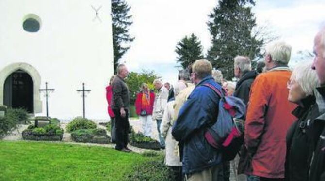 Gruorns Komitee-Vorsitzender Siegfried Fischer, links, mit Besuchern vor der Stephanuskirche des zerstörten Dorfes. GEA-FOTO: KU