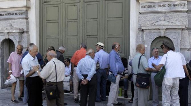 Menschen, darunter viele Rentner, stehen in Athen vor der National Bank of Greece. Foto: Orestis Panagiotou