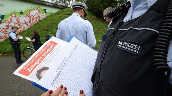 Eine Polizeibeamtin hält in Freiburg am Fundort ein Flugblatt mit einem Foto des getöten achtjährigen Armani in den Händen. F