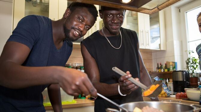 Backs und Bajerreh, rechts, beide Flüchtlinge aus Gambia, sorgen mit einem Gericht aus ihrer Heimat für eine exotische Note bei