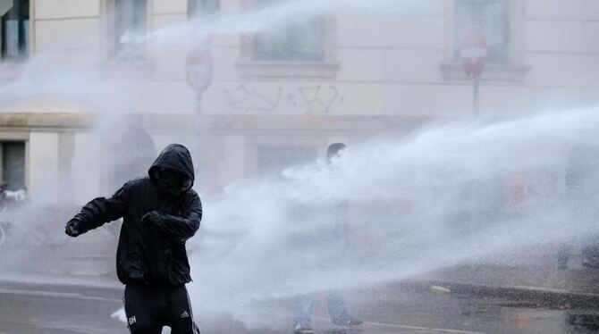 Flucht: Ein linker Gegendemonstrant versucht in Leipzig, dem Strahl eines Wasserwerfers zu entkommen. Foto: dpa