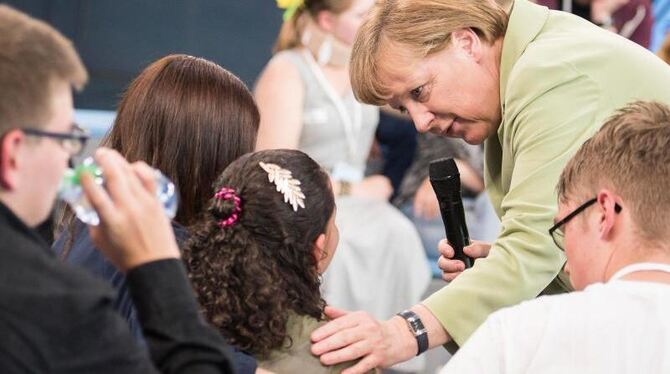 Dieser Moment machte Schlagzeilen: Bundeskanzlerin Merkel beugt sich in in Rostock zu dem Flüchtlingsmädchen Reem Sahwil heru