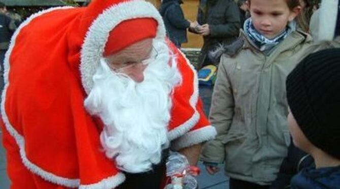 Weihnachtsmann verteilt Geschenke an Kinder auf dem Eninger Rathausplatz.  FOTO: KAB