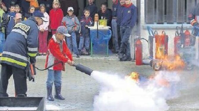 Ein junger Nachwuchsfeuerwehrmann macht dem Feuer den Garaus.  
FOTO: PR