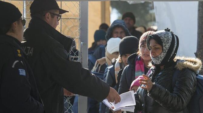 Mazedonische und griechische Beamte kontrollieren an der Grenze ihrer Länder die Dokumente von Flüchtlingen. Foto: Georgi Lic