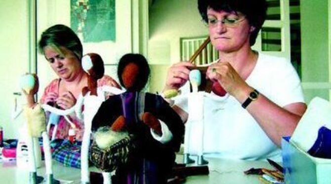 Gabriele Ruppert (rechts) und Beate Schneemann überziehen die Köpfe ihrer Egli-Figuren mit Stoff.  
FOTO: WEBER