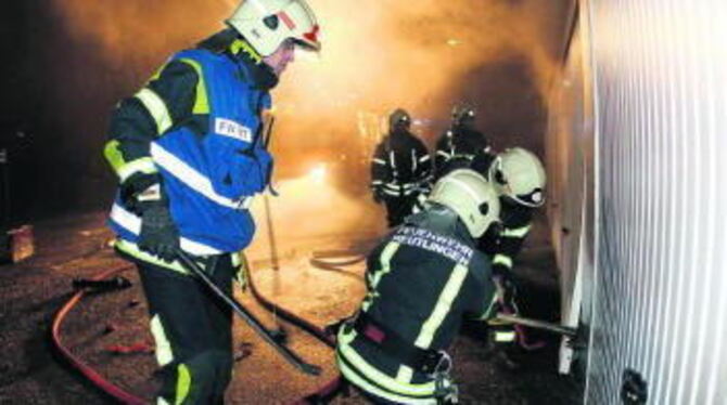 Wo Rauch ist, ist auch Feuer: Angehörige der Abteilung Stadtmitte öffnen mit Axt und Stemmeisen das Garagentor, hinter dem ein B