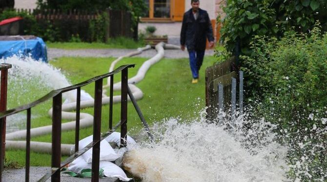 Ein Schlauch entwässert in Polling einen überfluteten Keller in einen Fluss. Foto: Karl-Josef Hildenbrand