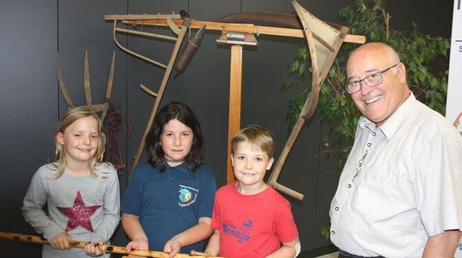 Jule Klett, Elif Senol und Jonas Klett (von links), alle acht Jahr alt und in der zweiten Klasse der Kirschenfeldschule, lassen sich den Dreschflegel von Rolf Breining erklären. FOTO: STB