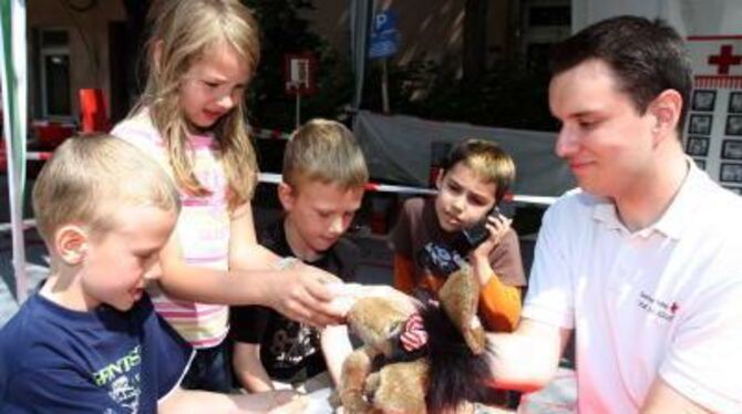 Bereitschafts-Sanitäter Michael Schmidt zeigt Kindern spielerisch, wie sie Nase, Arme und Beine vom Stoffelch fachmännisch verbi