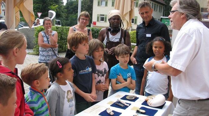 Ulrich Sauerborn, rechts, Leiter des Limes- und Urweltmuseums in Aalen, erläutert Kindern im Biosphärenzentrum spannende Funde a