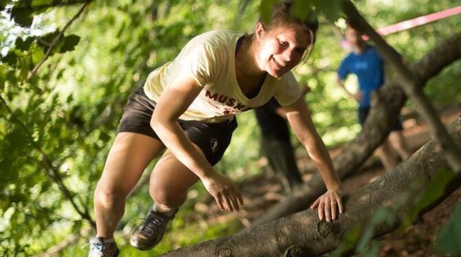 Lena klettert beim Training der Natural Athletes in Köln in einem Waldstück über einen Baum. Die Natural Athletes benutzen al