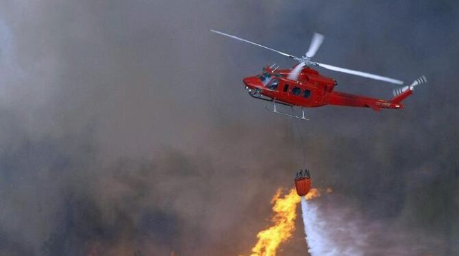 Von einem Helikopter aus versuchen Feuerwehrkräfte einen Brand mit Löschmittel im Naturschutzgebiet La Granadella in Valencia